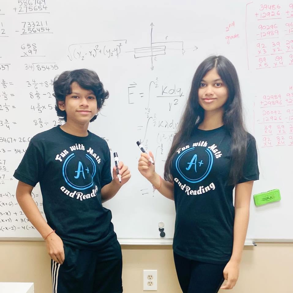 Two students in Fun With Math and Reading shirts in front of a math whiteboard